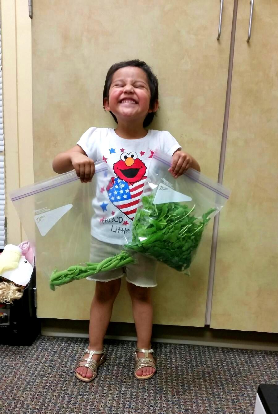 Photo of a smiling child holding a bag of vegetables.